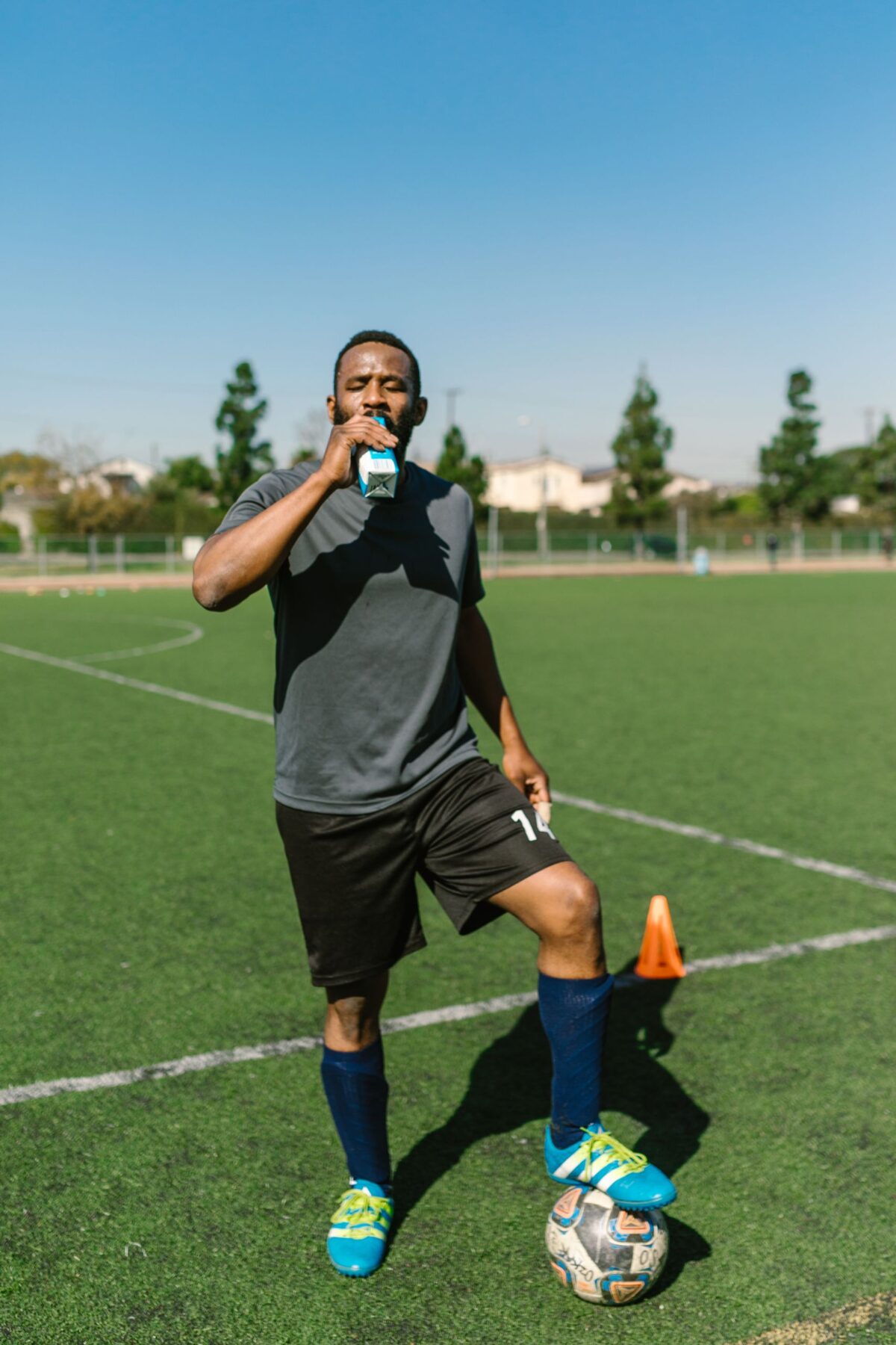 Elevated Mind, Body & Life Article: How to Beat Summer Fatigue. Athlete taking a break and hydrating on the soccer field during a sunny day.