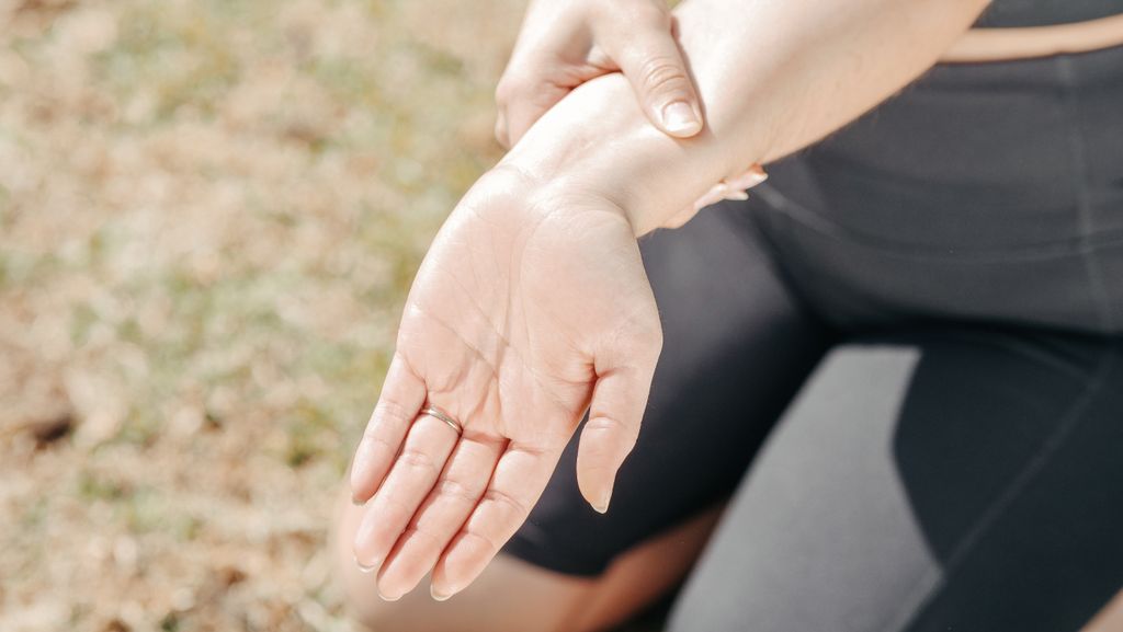How to beat summer fatigue: 3 important science-backed things you should know. Image of a person gripping wrist her wrist to feel pulse point.